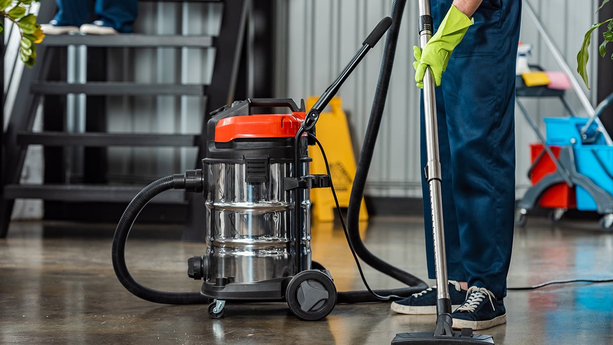 Uniformed Sizemore janitorial service worker vacuuming the floor of a commercial facility