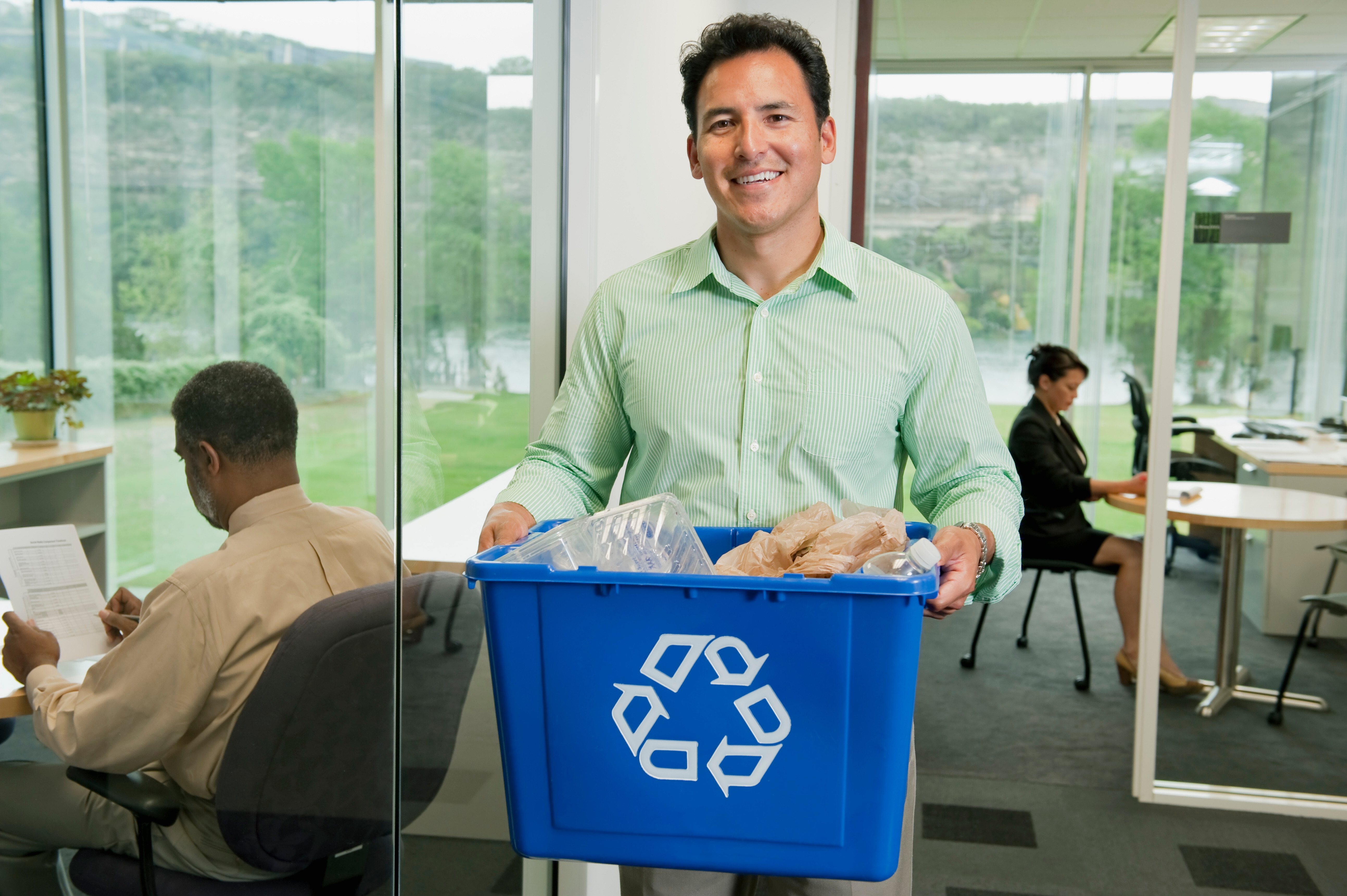 man-carrying-recycling-bin-in-bright-office-2026-03-25-02-17-17-utc